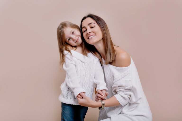Tendern portrait, funny, bright, cheerful young mother looks at the camera, whistles and hugging a daughter, family look, holiday, true emotions