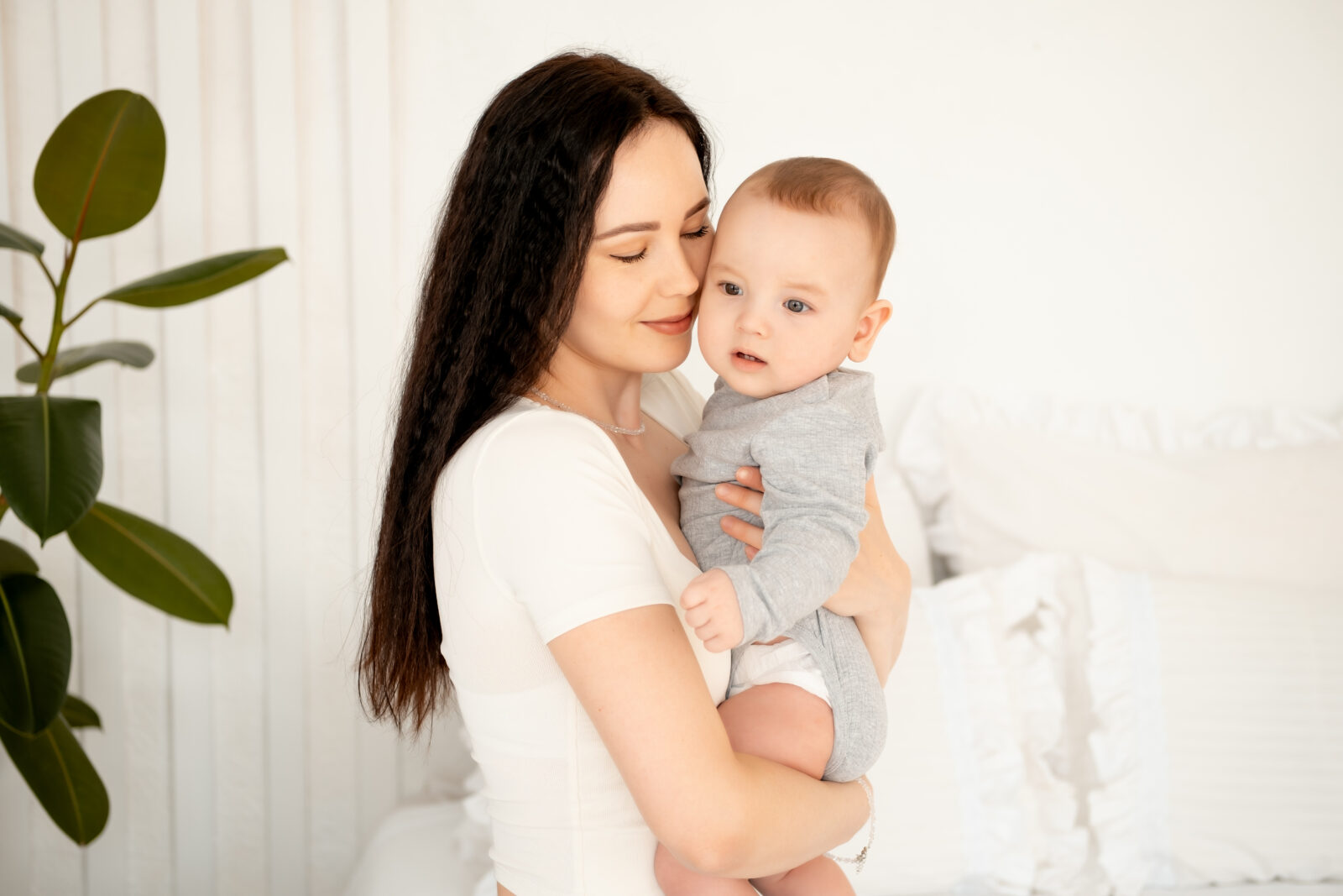 mom and baby, mother hugs and kisses baby holding him in her arms, maternal love and care, young mom having fun with baby baby, mom's decree