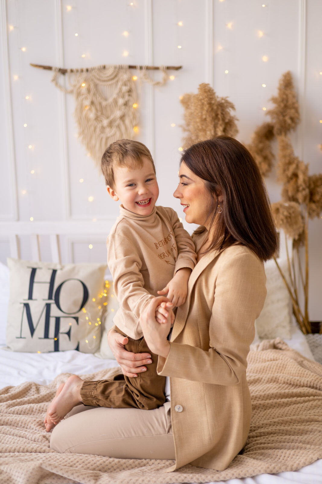 mom gently hugs a little baby boy at home on a bed in natural brown tones, a happy family with a small child has fun together