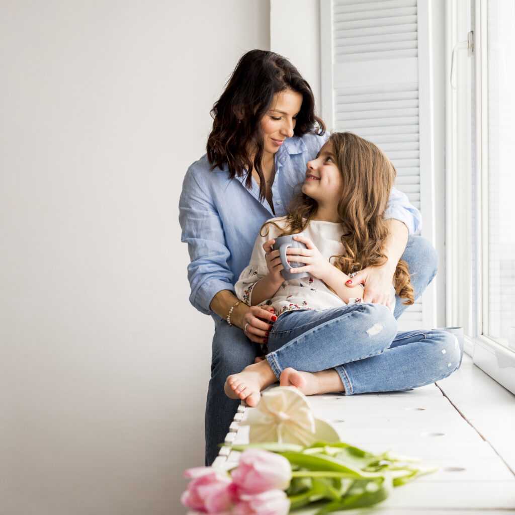 mother-hugging-daughter-from-window-sill